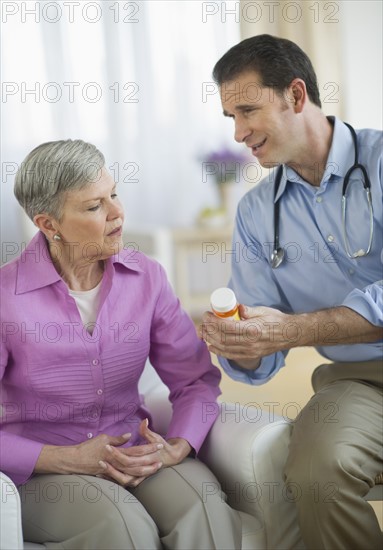 Smiling doctor giving medicine bottle to senior woman.