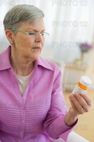 Senior woman looking at pill bottle.