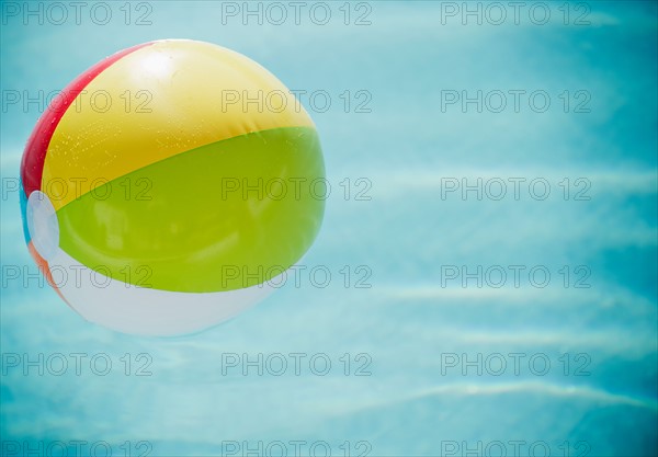 Close up of striped beach ball against water surface. Photo : Jamie Grill Photography