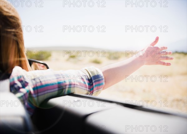 USA, California, Palm Springs, Coachella Valley, San Gorgonio Pass, Woman stretching arm outside convertible car. Photo : Jamie Grill Photography