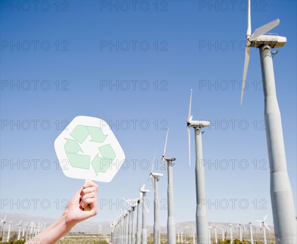 Woman's hand holding recycling sign