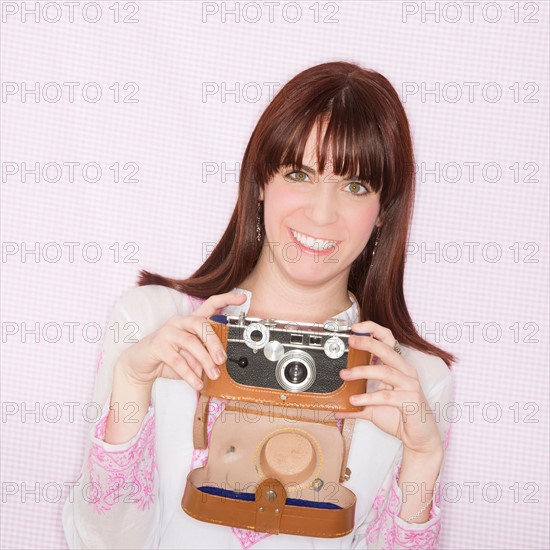 Studio portrait of young woman using still camera. Photo : Daniel Grill