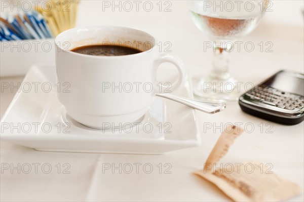 Close up of coffee cup and pda on table.