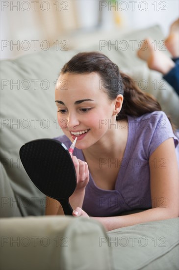 Teenage girl (14-15) applying lipstick.