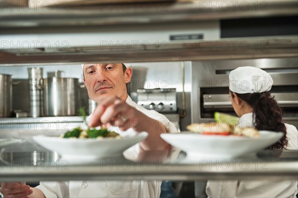 Chefs preparing food in kitchen.