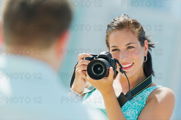 Portrait of young woman taking pictures with camera.