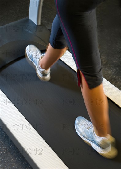 Low section of woman walking on treadmill.