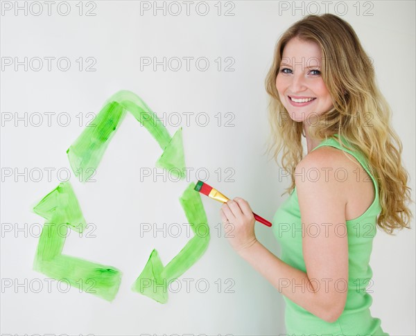 Woman painting green recycling sign. Photo : Jamie Grill