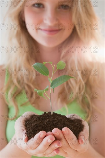 Young woman with seedling. Photo : Jamie Grill