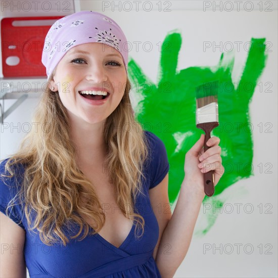 Young woman painting with green paint. Photo : Jamie Grill