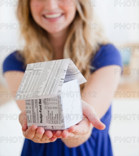 Young woman holding paper house. Photo : Jamie Grill