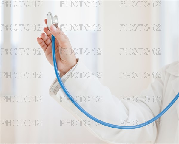 Close up of female doctor's hand holding stethoscope. Photo : Jamie Grill
