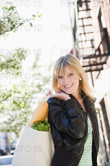 USA, New York, Williamsburg, Brooklyn, Smiling woman carrying shopping bag. Photo: Jamie Grill