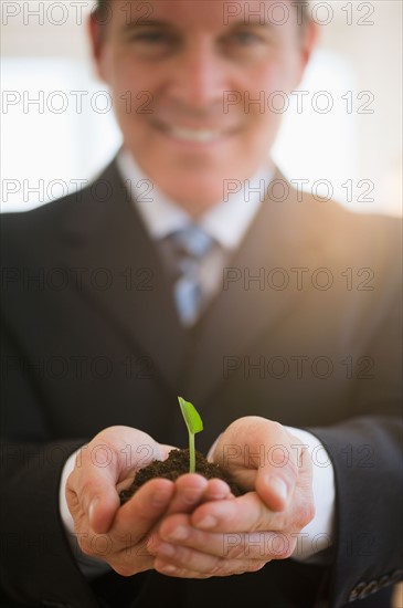 Businessman holding seedling. Photo : Jamie Grill