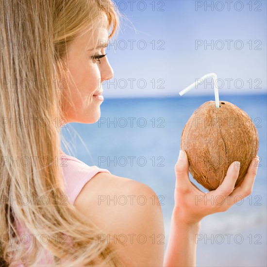 Profile of woman holding coconut with straw. Photo : Jamie Grill