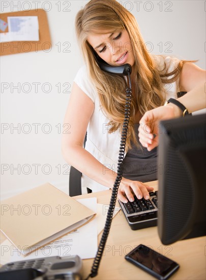 Businesswoman working at desk in office. Photo : Jamie Grill