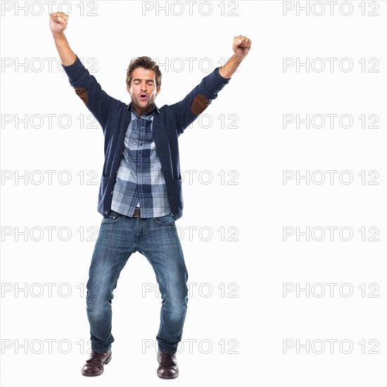 Studio shot of young man celebrating with arms raised. Photo: momentimages