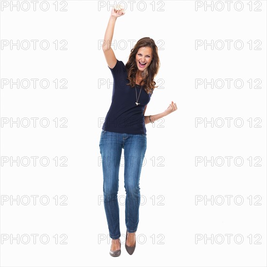 Studio shot of young woman celebrating with arm raised. Photo: momentimages