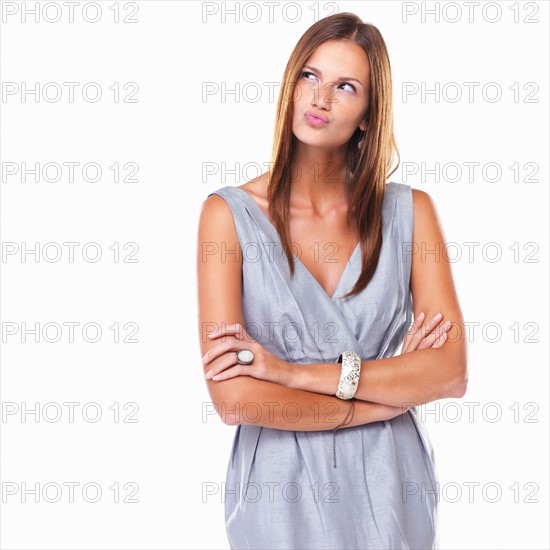 Thoughtful woman standing with hands folded and pursing her lips. Photo: momentimages