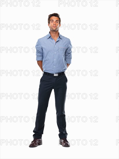 Studio shot of young business man standing with hands behind back. Photo: momentimages