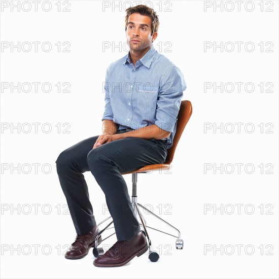 Studio shot of pensive business man sitting on chair. Photo: momentimages