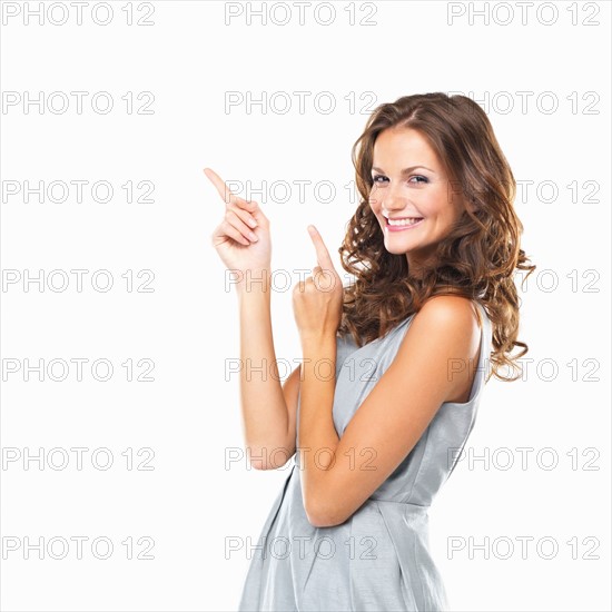 Studio portrait of beautiful smiling woman pointing upwards. Photo : momentimages