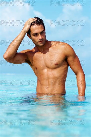 Smart young guy taking a bath in the ocean. Photo : momentimages