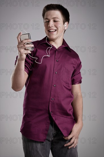 Portrait of smiling teenager listening mp3 player, studio shot. Photo : Rob Lewine