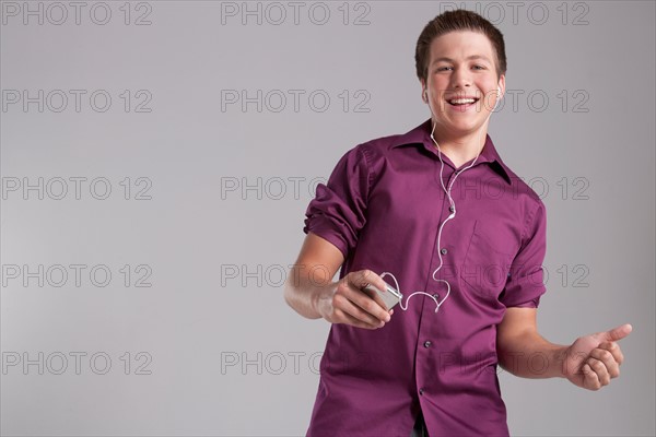 Portrait of smiling teenager listening mp3 player, studio shot. Photo: Rob Lewine