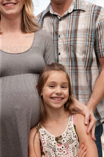 Pregnant mother, father and daughter (6-7) posing for portrait. Photo : Rob Lewine