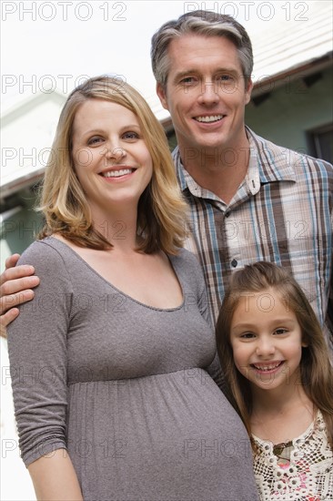 Pregnant mother, father and daughter (6-7) posing for portrait. Photo : Rob Lewine