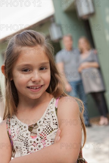 Portrait of cheerful girl (6-7) with parents in background. Photo : Rob Lewine