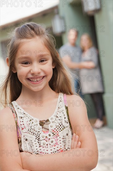 Portrait of cheerful girl (6-7) with parents in background. Photo : Rob Lewine