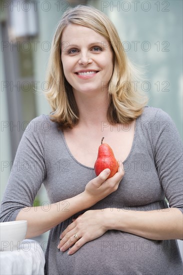 Pregnant woman holding pear. Photo : Rob Lewine