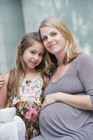 Portrait of pregnant mother and daughter (6-7)embracing. Photo : Rob Lewine