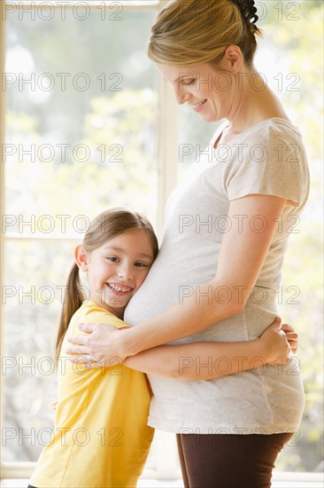 Daughter (6-7) embracing pregnant mother. Photo : Rob Lewine