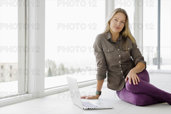 Mature woman sitting on floor with laptop. Photo : Rob Lewine