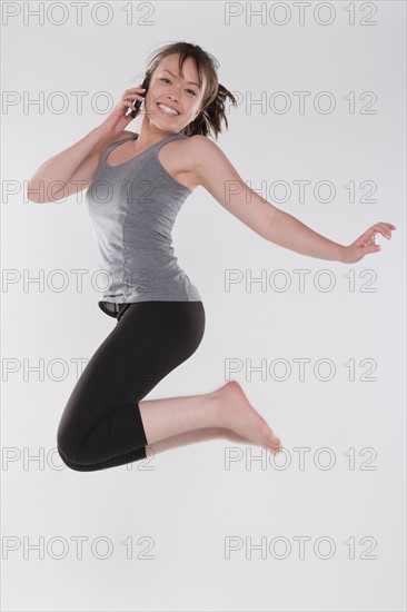 Portrait of young woman jumping, studio shot. Photo : Rob Lewine