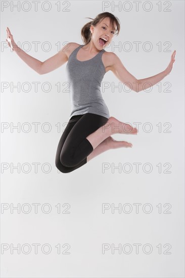 Portrait of young woman jumping, studio shot. Photo : Rob Lewine