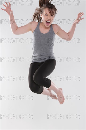 Portrait of young woman jumping, studio shot. Photo: Rob Lewine