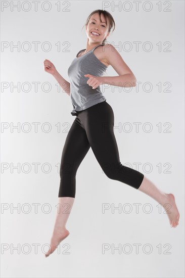 Portrait of young woman jumping, studio shot. Photo: Rob Lewine