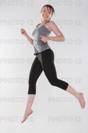 Portrait of young woman jumping, studio shot. Photo : Rob Lewine