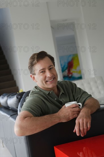 Mature man relaxing on sofa. Photo : Rob Lewine