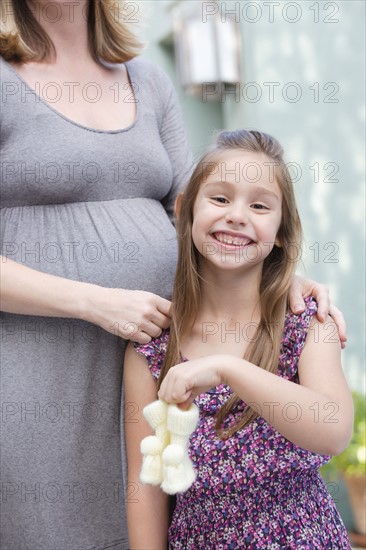 Pregnant mother standing with daughter (6-7) holding baby booties . Photo: Rob Lewine