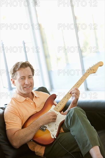 Mature man playing guitar. Photo : Rob Lewine