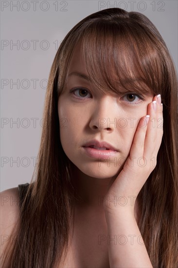 Portrait of young woman with tooth ache, studio shot. Photo : Rob Lewine