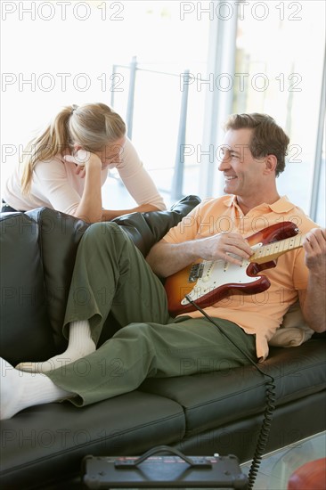 Mature man playing guitar while woman listening. Photo: Rob Lewine