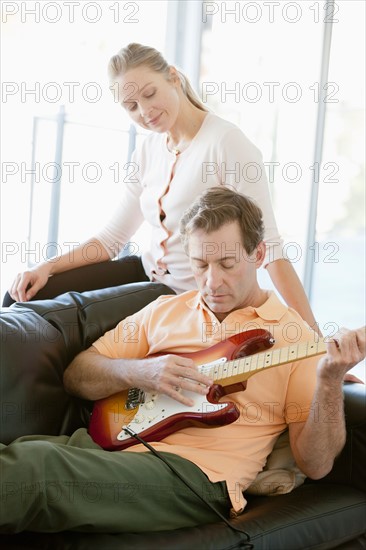 Mature man playing guitar while woman listening. Photo : Rob Lewine