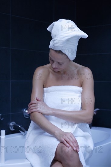 Mature woman sitting in bathroom wrapped in towel. Photo: Rob Lewine