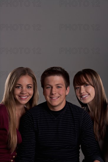 Portrait of teenage boy (16-17) and girl (16-17) with young friend, studio shot. Photo : Rob Lewine